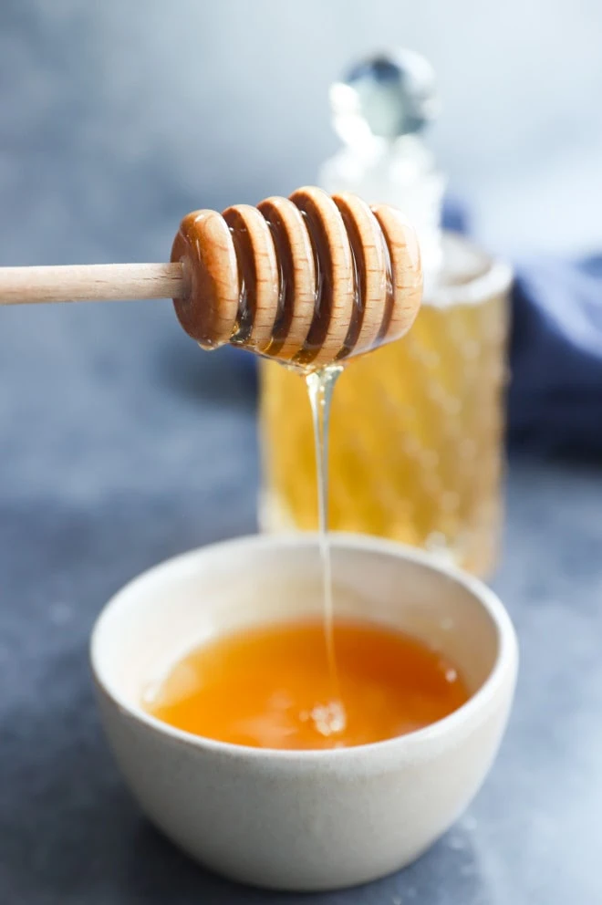 drizzling honey from a honey stick into a bowl