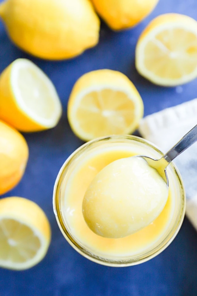 spoonful of lemon curd with lemons in the background