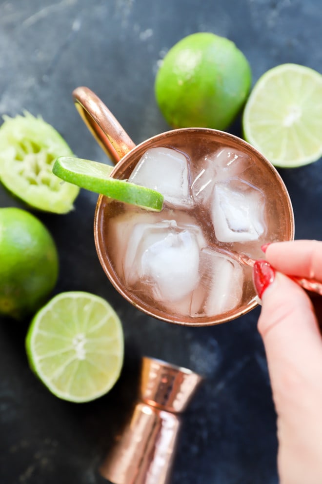 stirring together london mule cocktail in copper mug