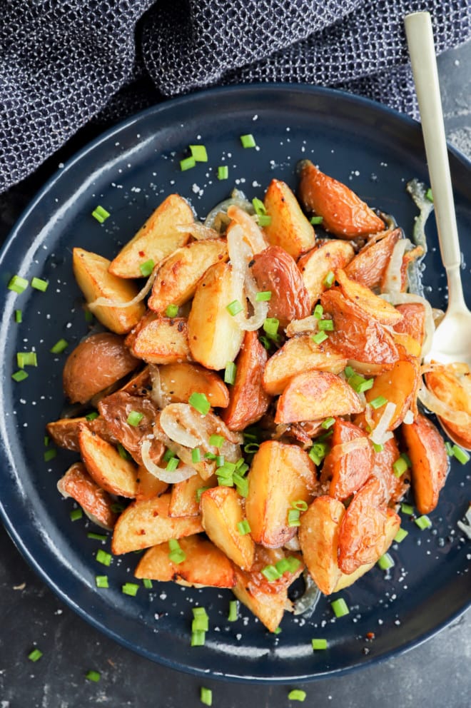 oven fried potatoes and onions on plate with chives and salt