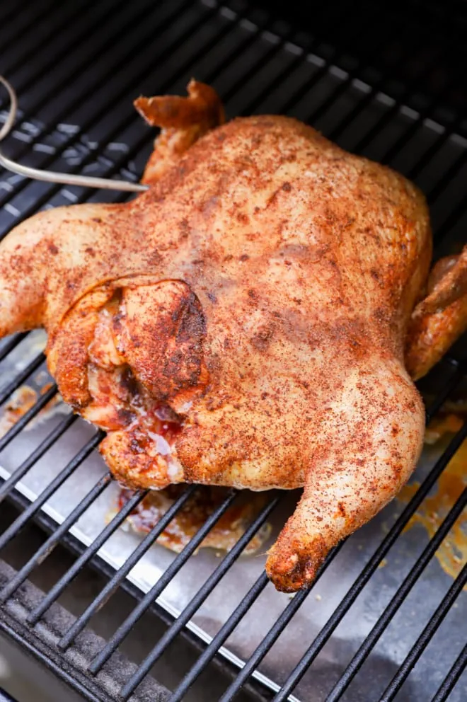 Smoked chicken on grill while cooking with meat thermometer
