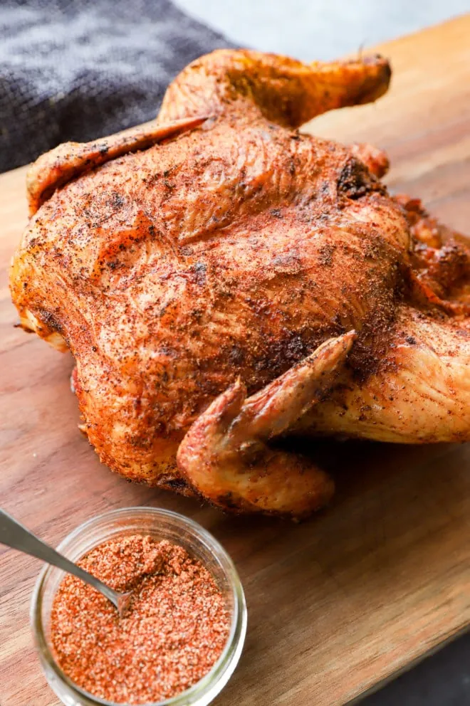 Poultry on cutting board with dry rub and spoon