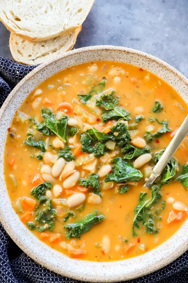 Italian vegetable stew in a bowl with bread and a spoon