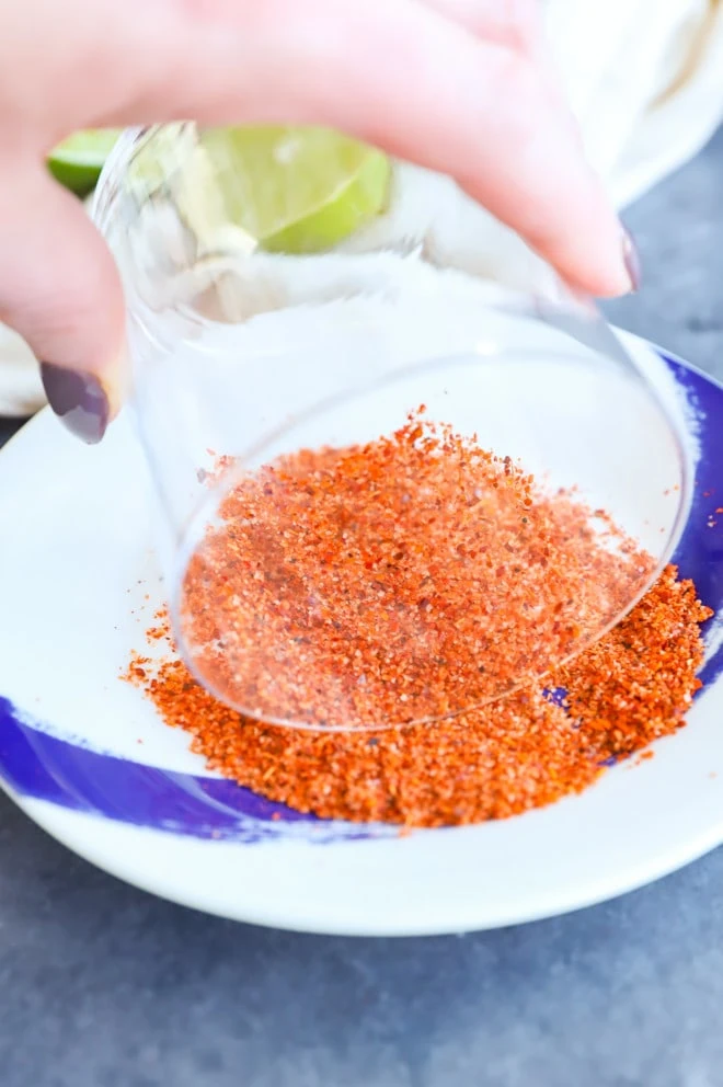 rimming a cocktail glass with Tajin seasoning