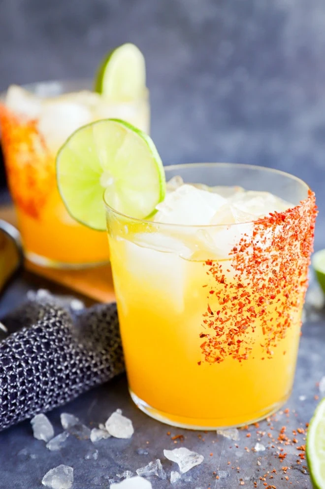 passion fruit margaritas in glasses with tajin rim and lime wheel garnish