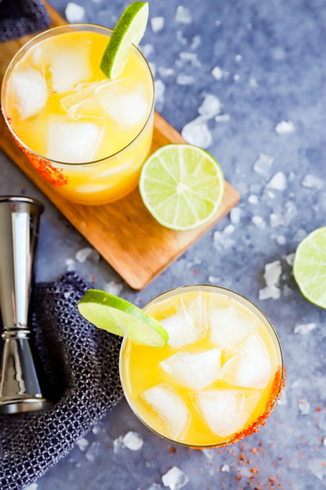 Ice surrounding cocktails in glasses with limes and jigger