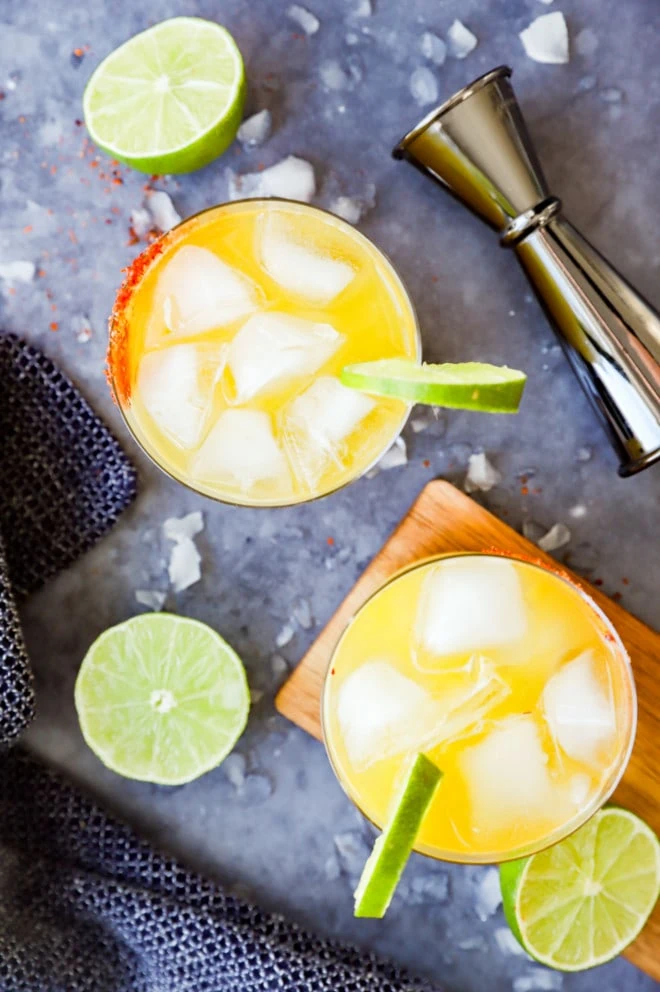 Glasses of orange cocktail with lime slices and jigger