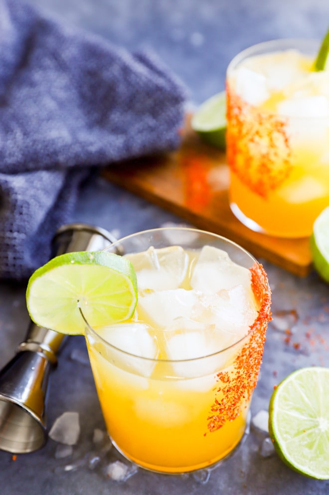 Passion fruit margarita in a glass rimmed with Tajin and jigger in the background