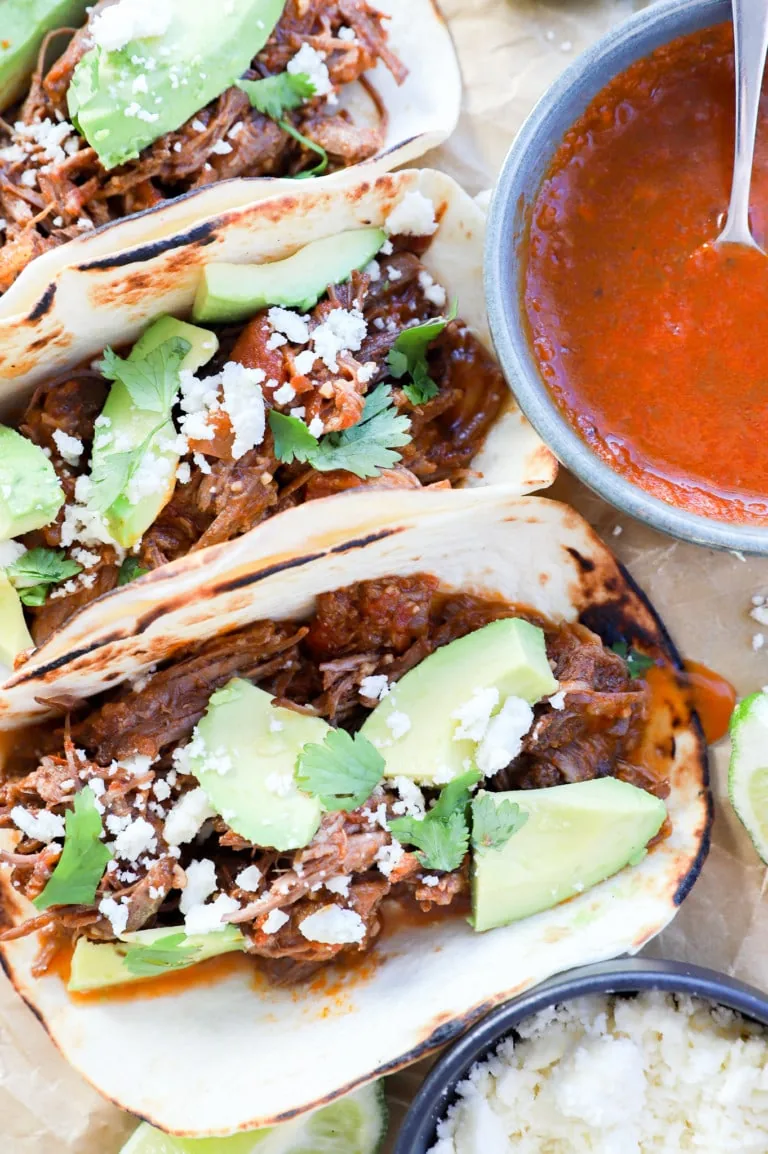 overhead image of shredded beef tacos and toppings