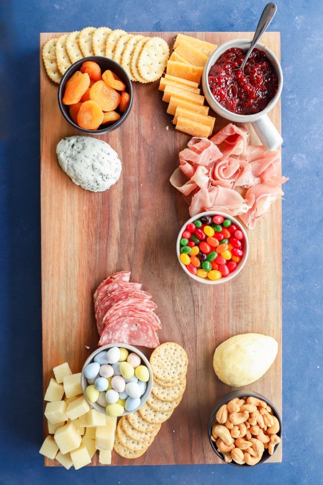 cheeses and meats being added to a charcuterie board