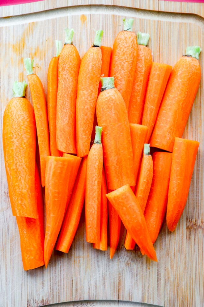 Carrots on a cutting board cut in half and peeled