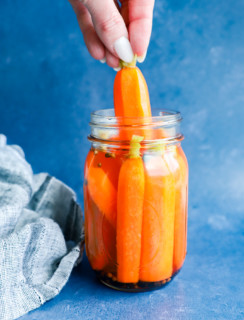 hand pulling out a quick pickled carrot from a jar