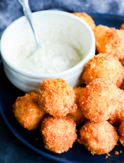 Crispy cheesy snacks on a plate in a pile with dipping sauce