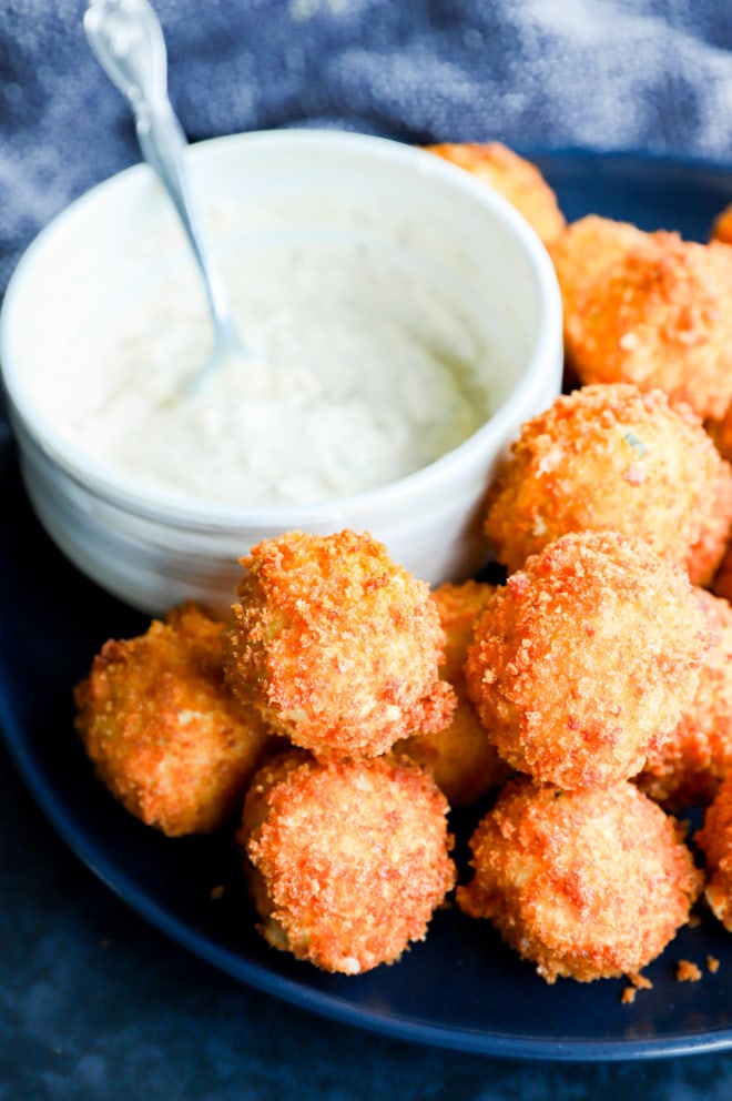 Crispy cheesy snacks on a plate in a pile with dipping sauce
