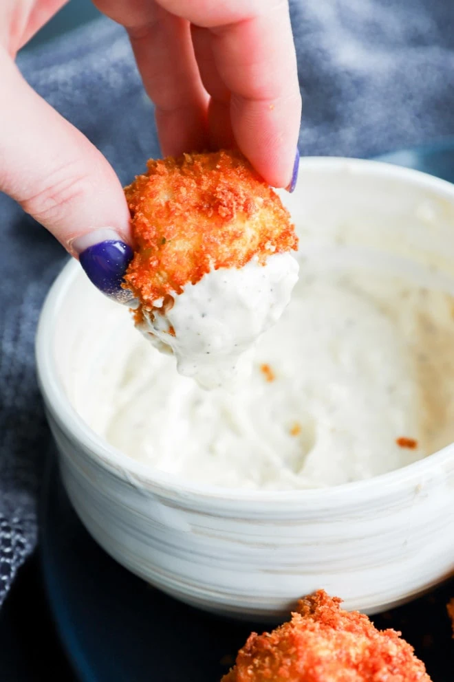 hand holding a panko crispy snack with aioli on it