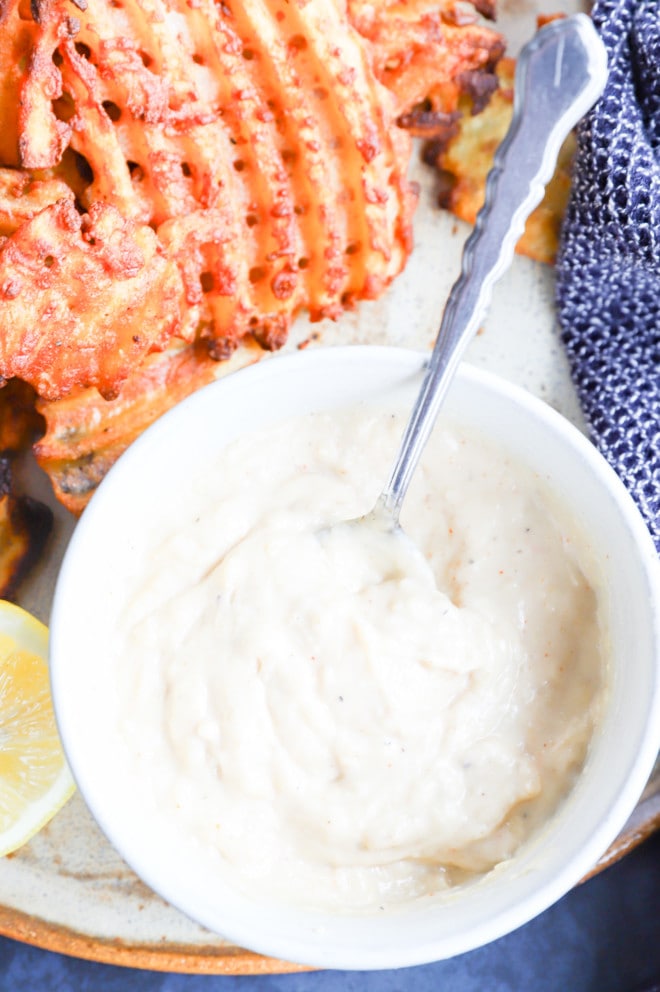 bowl of roasted garlic aioli with a plate of fries