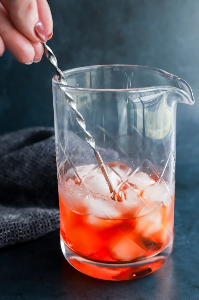 Stirring an aperol negroni in a mixing glass