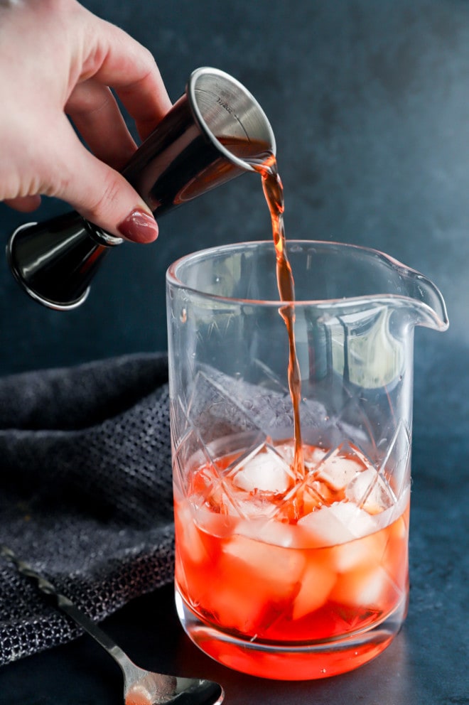 Pouring aperol into a mixing glass with ice