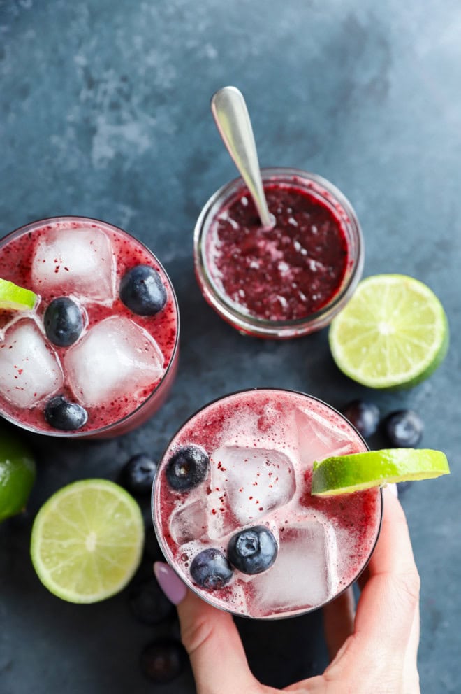 hand holding a glass with a blueberry margarita