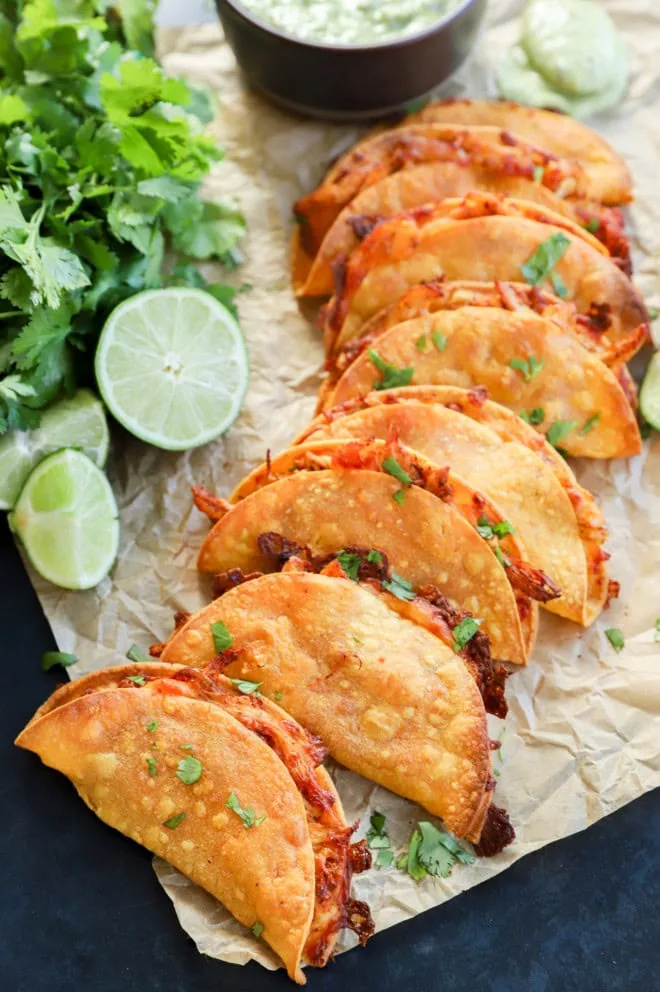 crispy chicken tacos on parchment with avocado tomatillo salsa