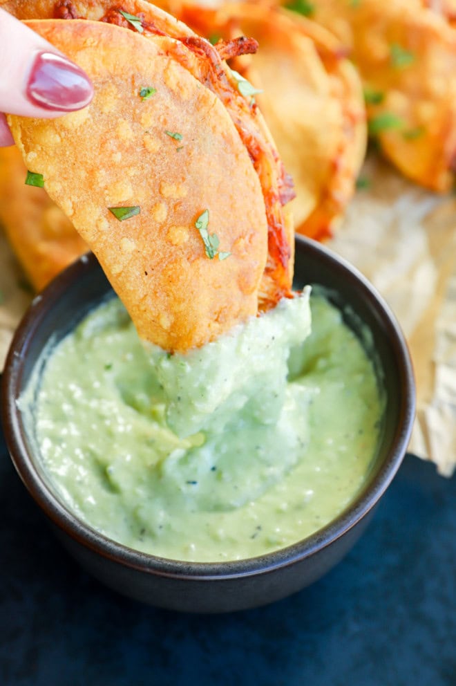 Dipping a tortilla with filling into avocado tomatillo sauce