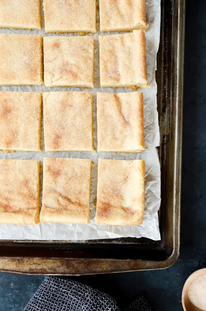 overhead image of snickerdoodle bars on a sheet pan with parchment paper
