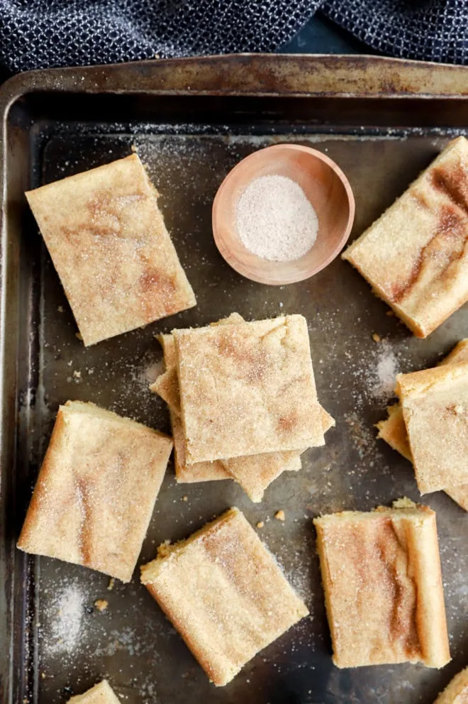 snickerdoodle bars on a metal sheet pan with cinnamon sugar