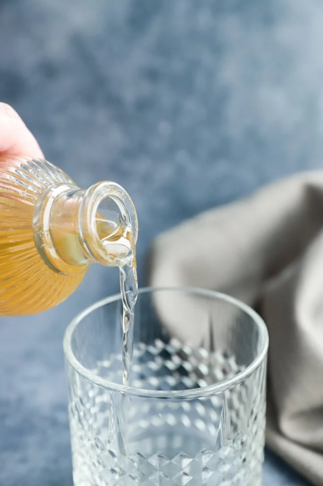 pouring vanilla simple syrup into a cocktail glass