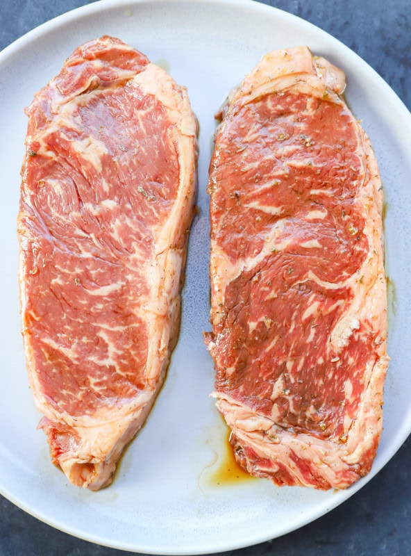 Marinated steaks on a plate new york strip steak