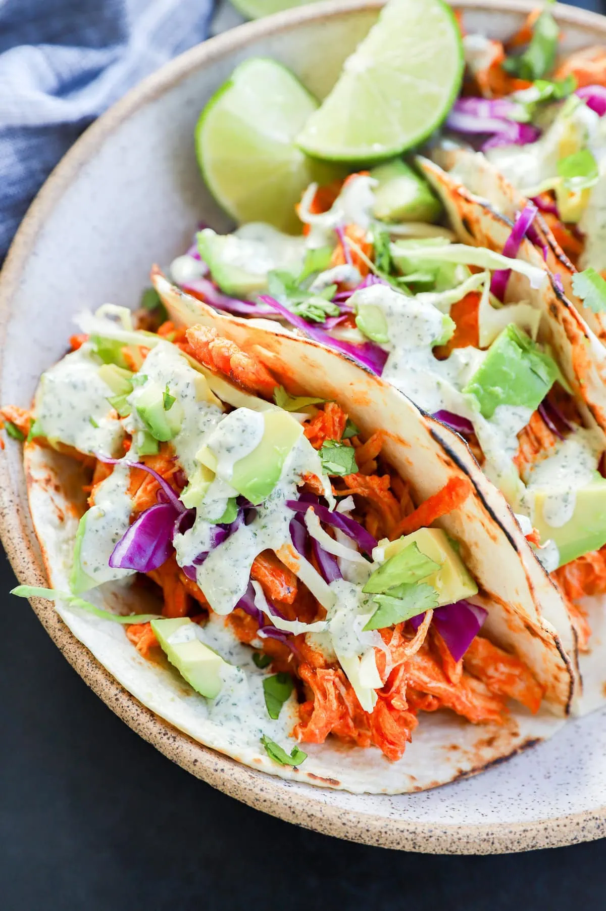 buffalo chicken tacos with cabbage and avocado on top