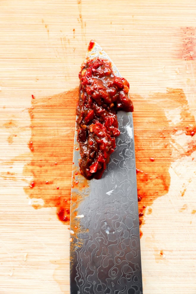 chopped chipotle peppers on a knife on a cutting board