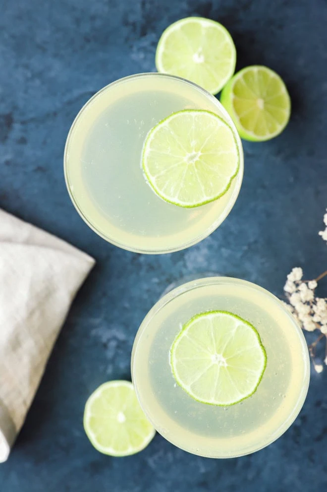 sparkling wine cocktail in a coupe glass with fresh limes