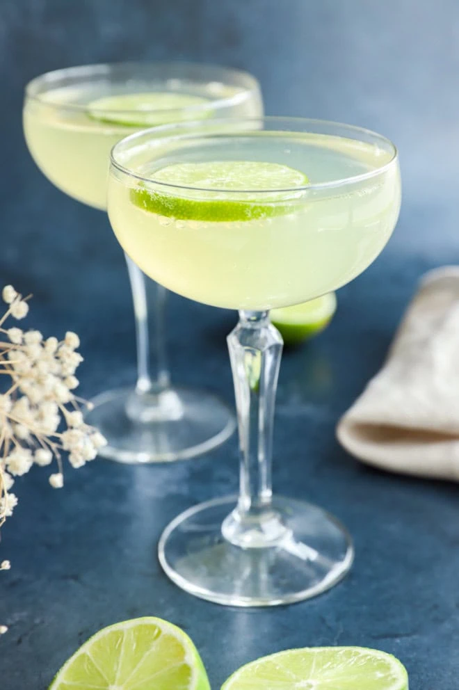 elderflower cocktail in glasses with limes and flowers in the background
