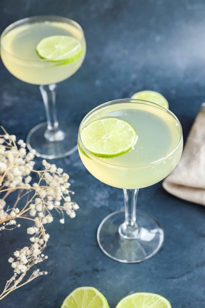 champagne drinks in cocktail glasses with flowers and limes in the background