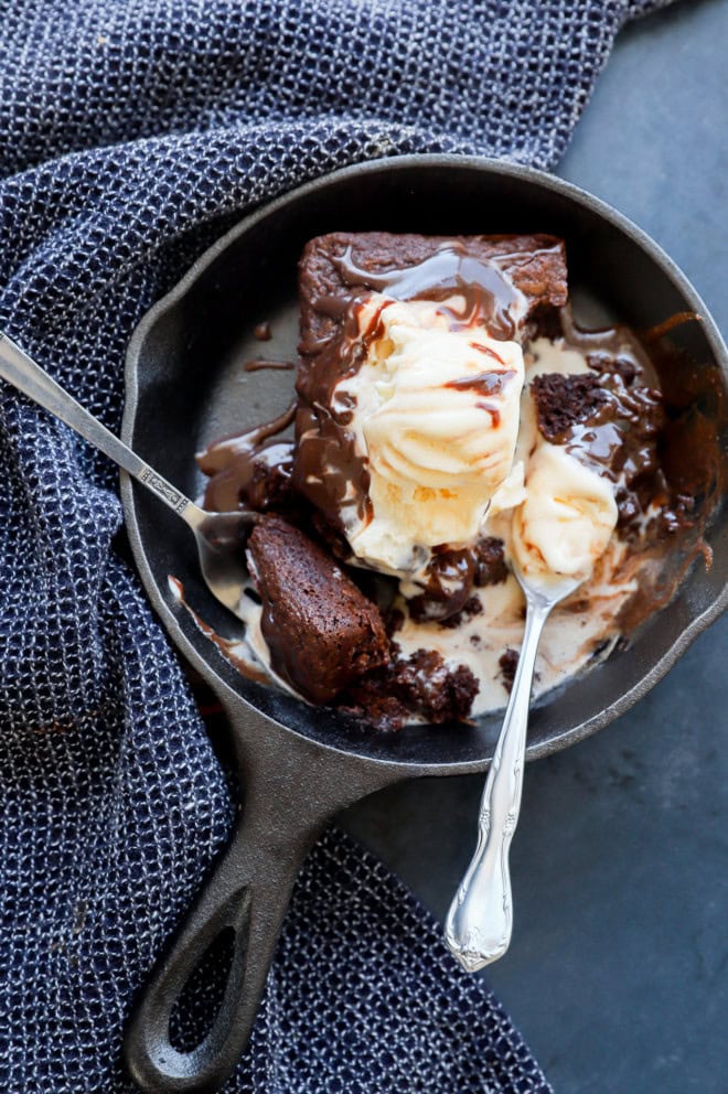 Ice cream on top of a sizzling brownie with hot fudge sauce and forks