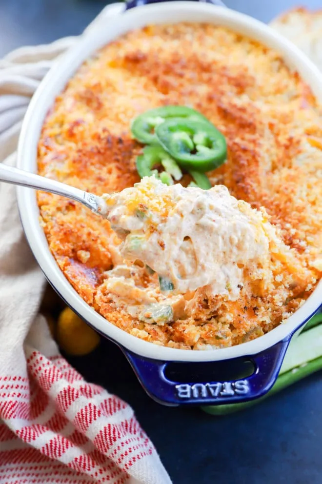 Cheesy dip being lifted with a spoon out of the pan