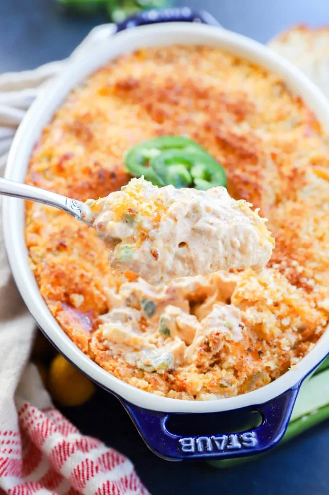 cheesy appetizer on a spoon lifted out of baking pan with jalapeno slices