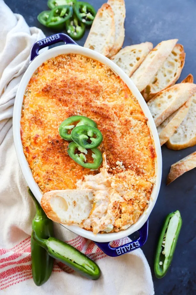 bread slice in a pan of jalapeno popper dip