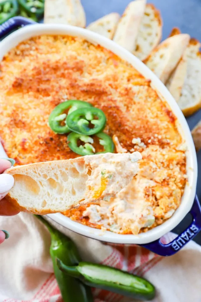 hand holding bread slice with creamy cheese dip on it