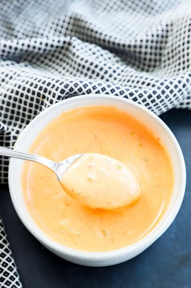 Spoon lifting out bang bang shrimp sauce of a bowl