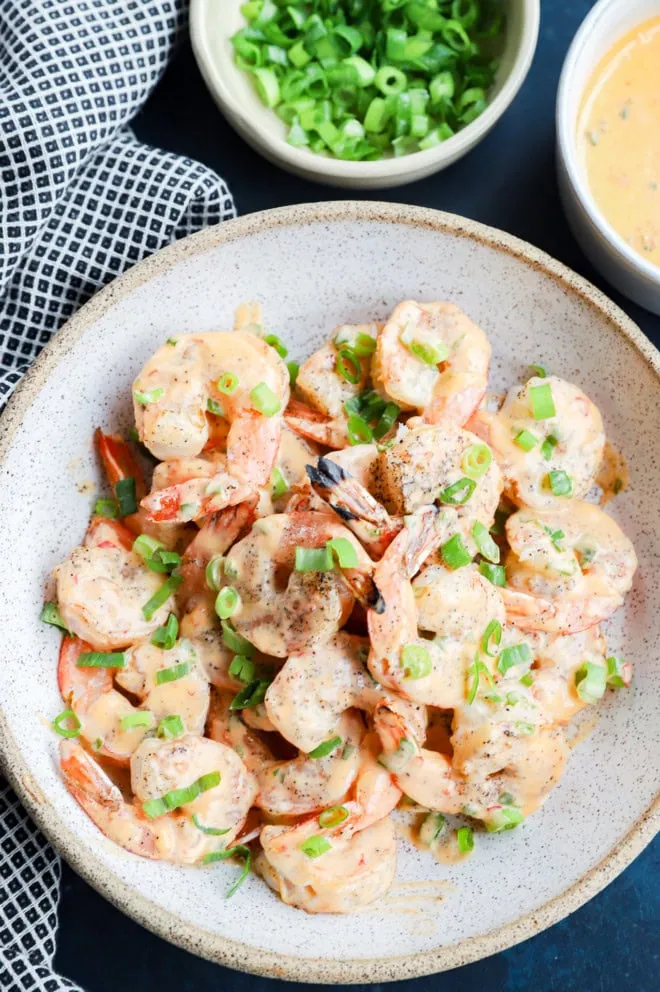 Grilled bang bang shrimp in a bowl with green onion sprinkled on top