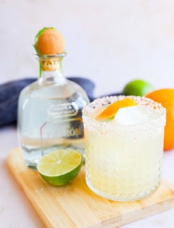 Patron bottle with a margarita in a salt rimmed glass and citrus garnish