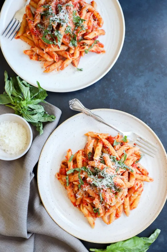 Plates of pasta with fresh basil leaves and freshly grated parmesan cheese