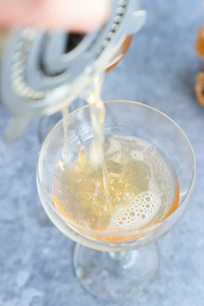 straining a cocktail into a coupe glass