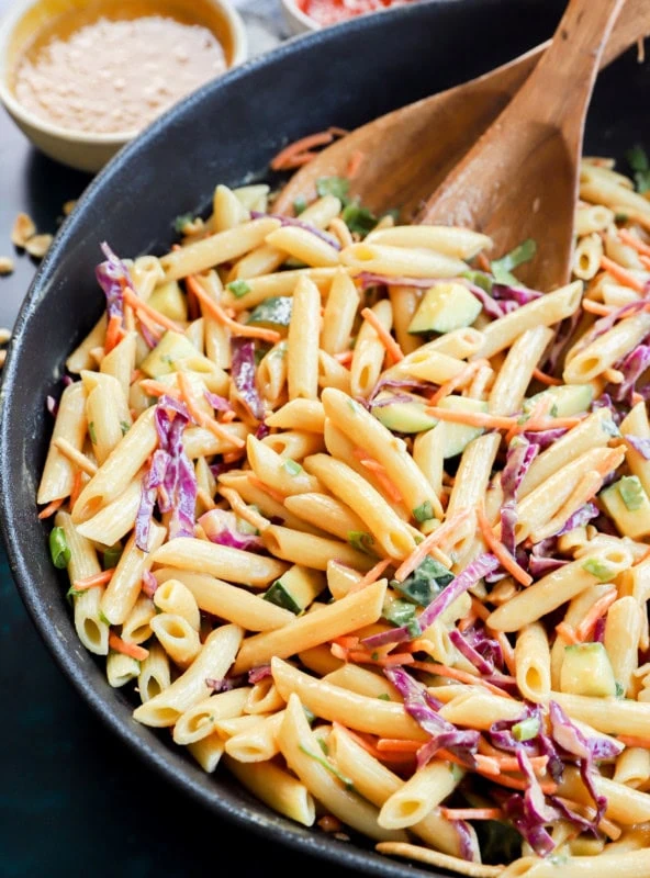 thai pasta salad in a large bowl with wooden utensils
