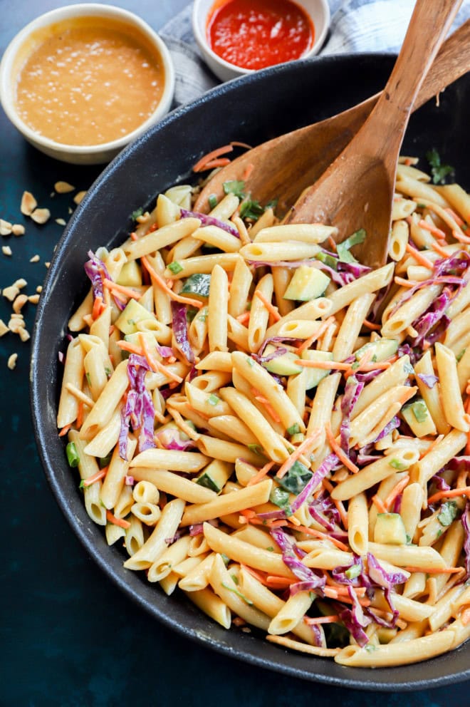 Bowl of noodle side dish with peanut dressing and sriracha