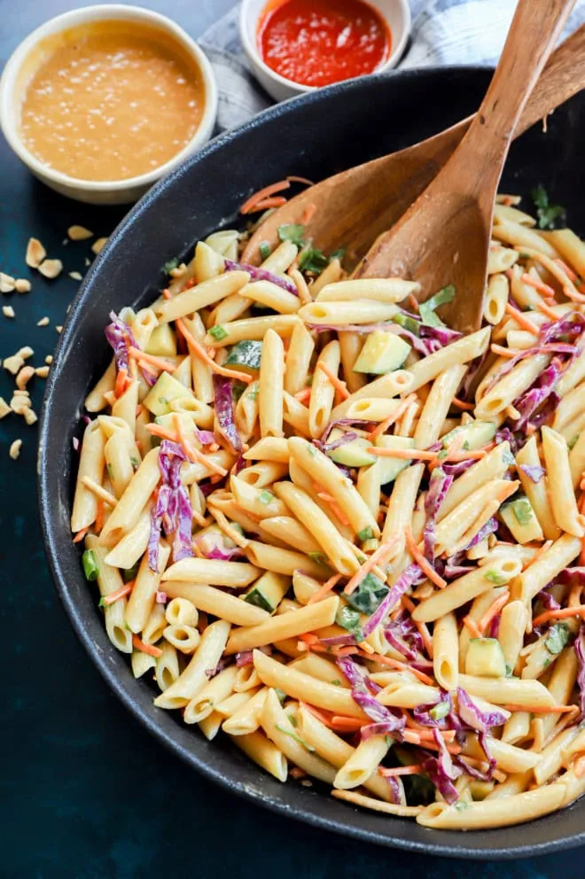 Bowl of noodle side dish with peanut dressing and sriracha