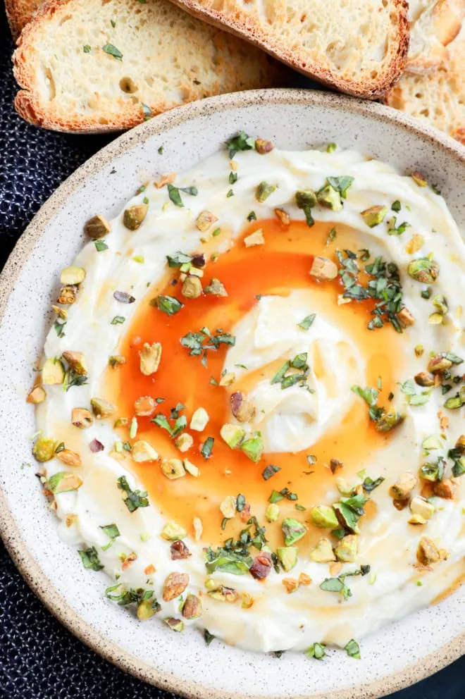 Creamy dip in a bowl with honey on top with slices of bread