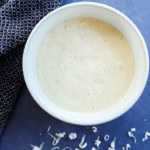 homemade caesar salad dressing in a bowl with cheese on the side