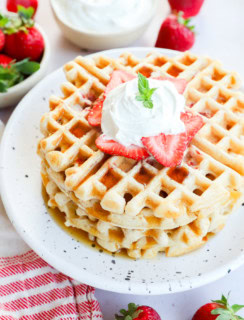 Stack of strawberry waffles with syrup on top